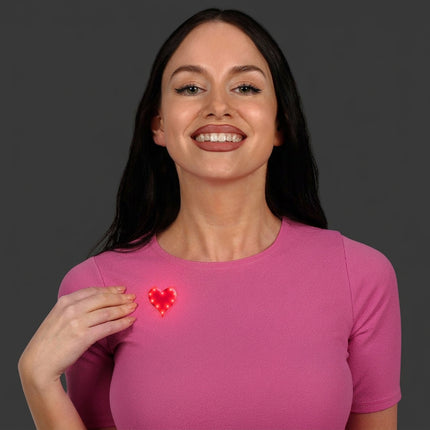 Red LED heart pin worn on a pink shirt