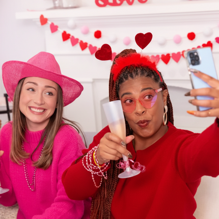 Two people celebrating with champagne flutes in a festive setting with heart head blooper