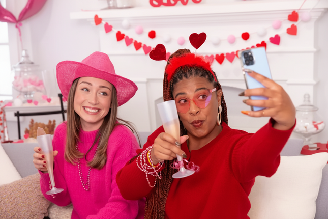Two people celebrating with champagne flutes in a festive setting with heart head blooper